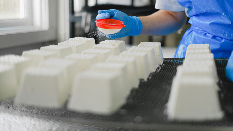 Frau stäubt mit einem Sieb Puder auf Käse