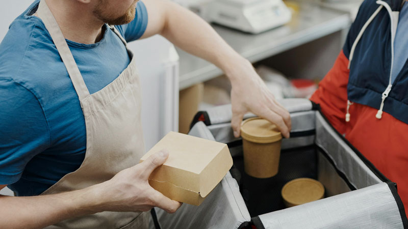 Mann stellt Essensboxen in eine Wärmetasche